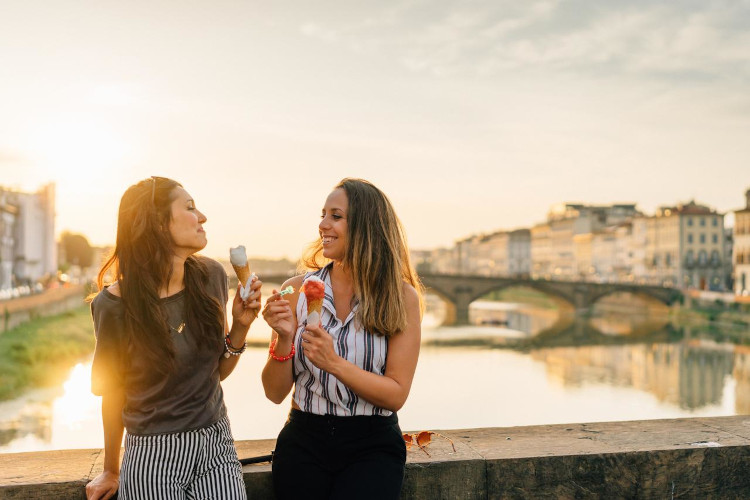 Zwei Frauen essen ein Eis auf einer alten Brücke in Venedig, Sonne steht schon tief